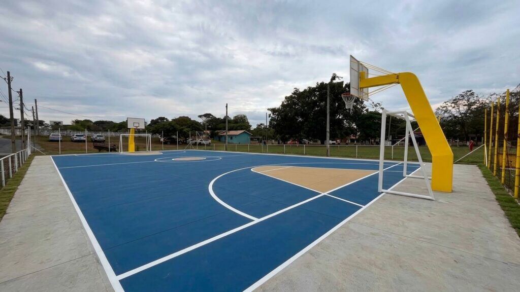Quadra poliesportiva com traves de futsal e tabelas de basquete