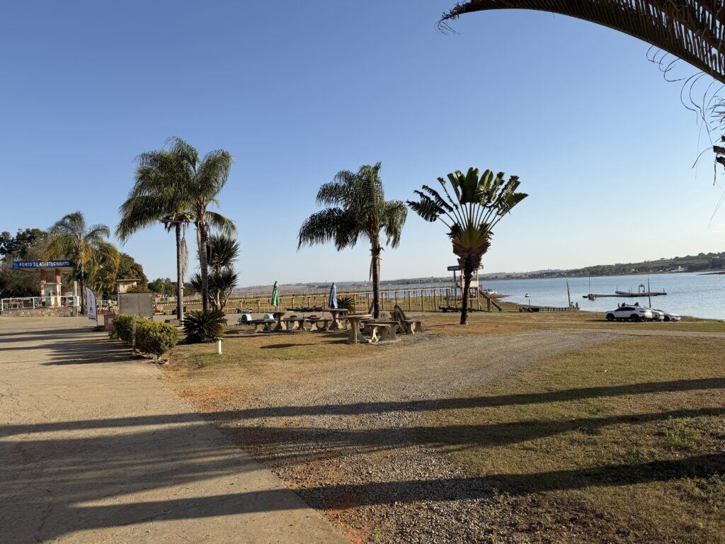 Orla do clube com palmeiras, mesas e o lago de Furnas ao fundo