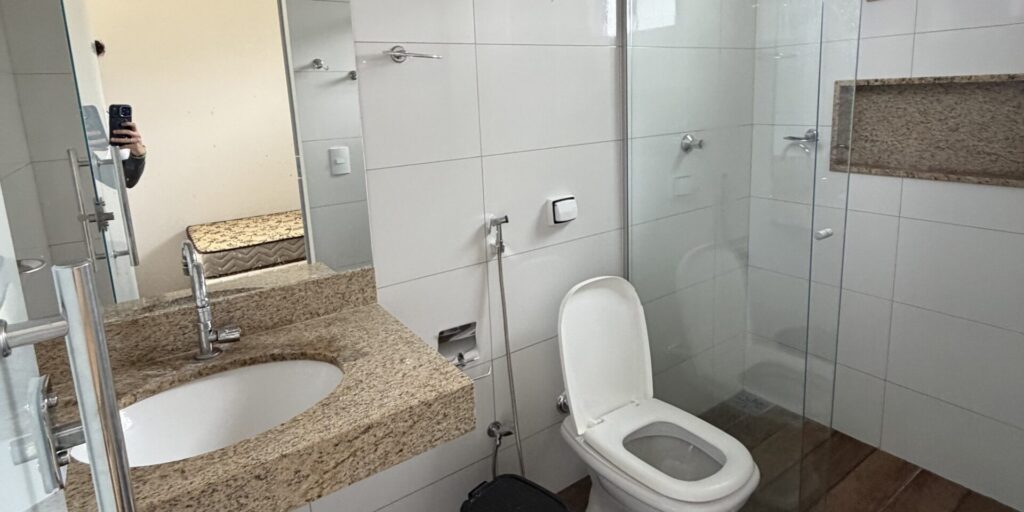 Banheiro de chalé com bancada de granito, vaso e box de vidro